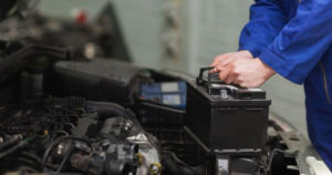 Mechanic removing car battery from engine bay
