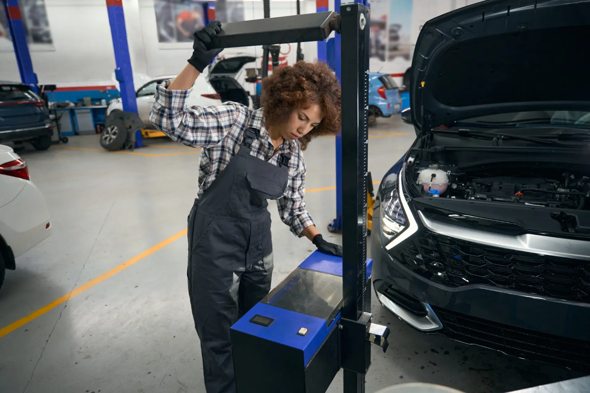 Mechanic checking car headlights with alignment equipment
