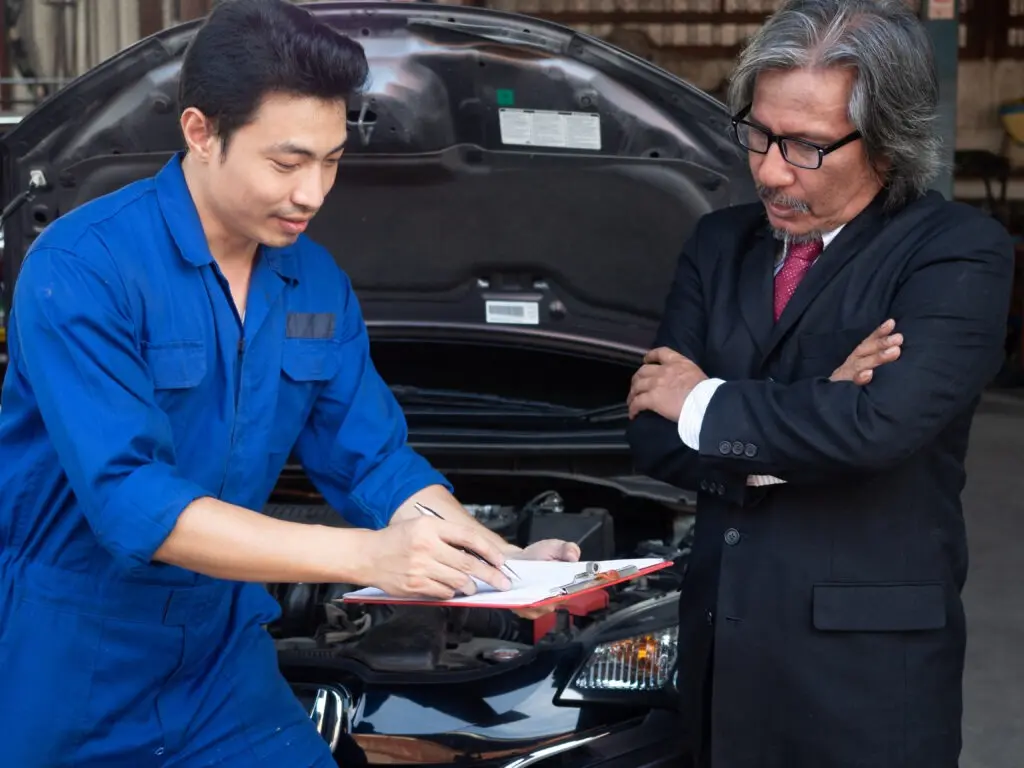 Mechanic showing car inspection report to customer