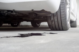 Dark fluid leaking onto the ground beneath the rear bumper of a white car