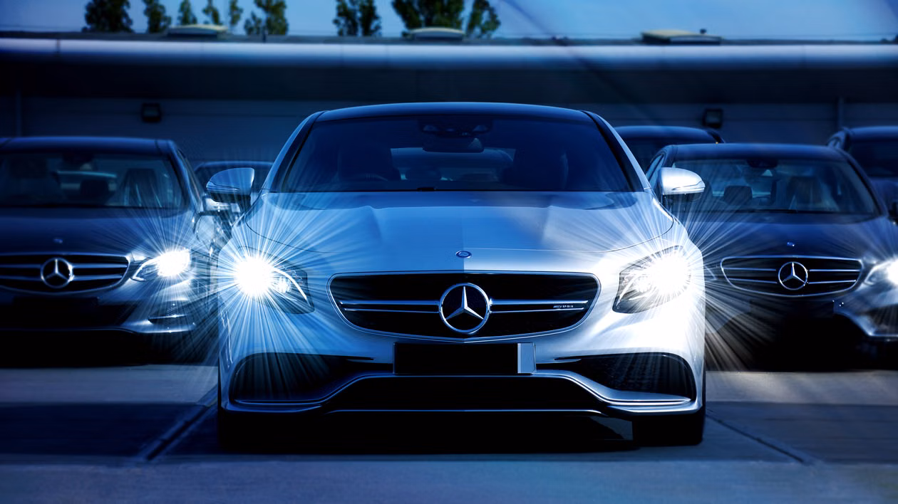 Three Mercedes-Benz cars parked with headlights on