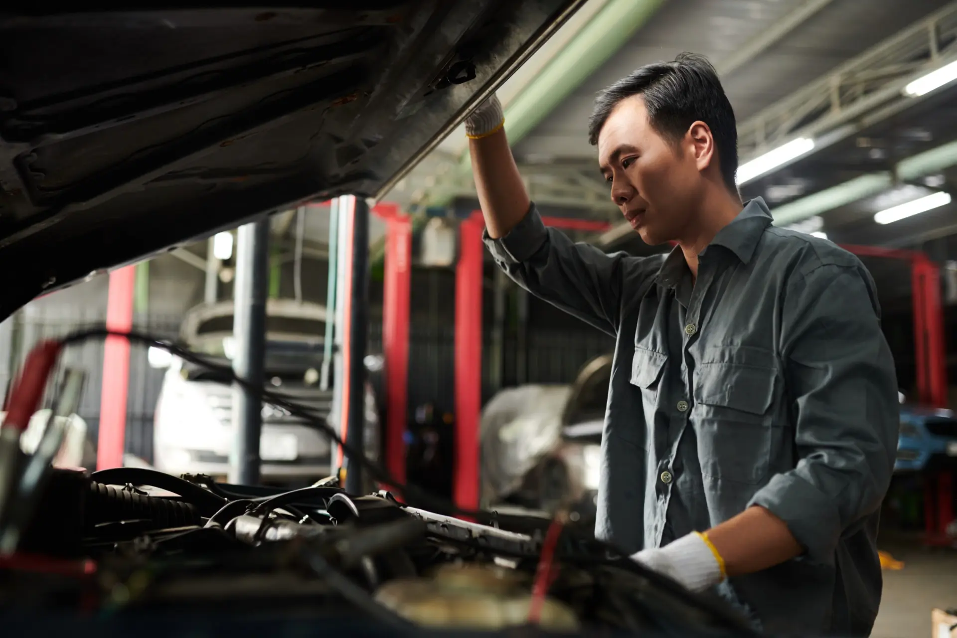 Mechanic inspecting car engine in a garage